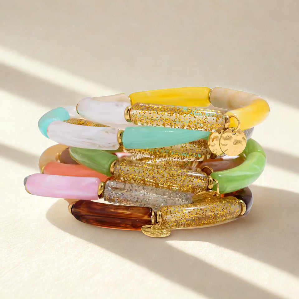 Stack of colorful acrylic bracelets on a light background