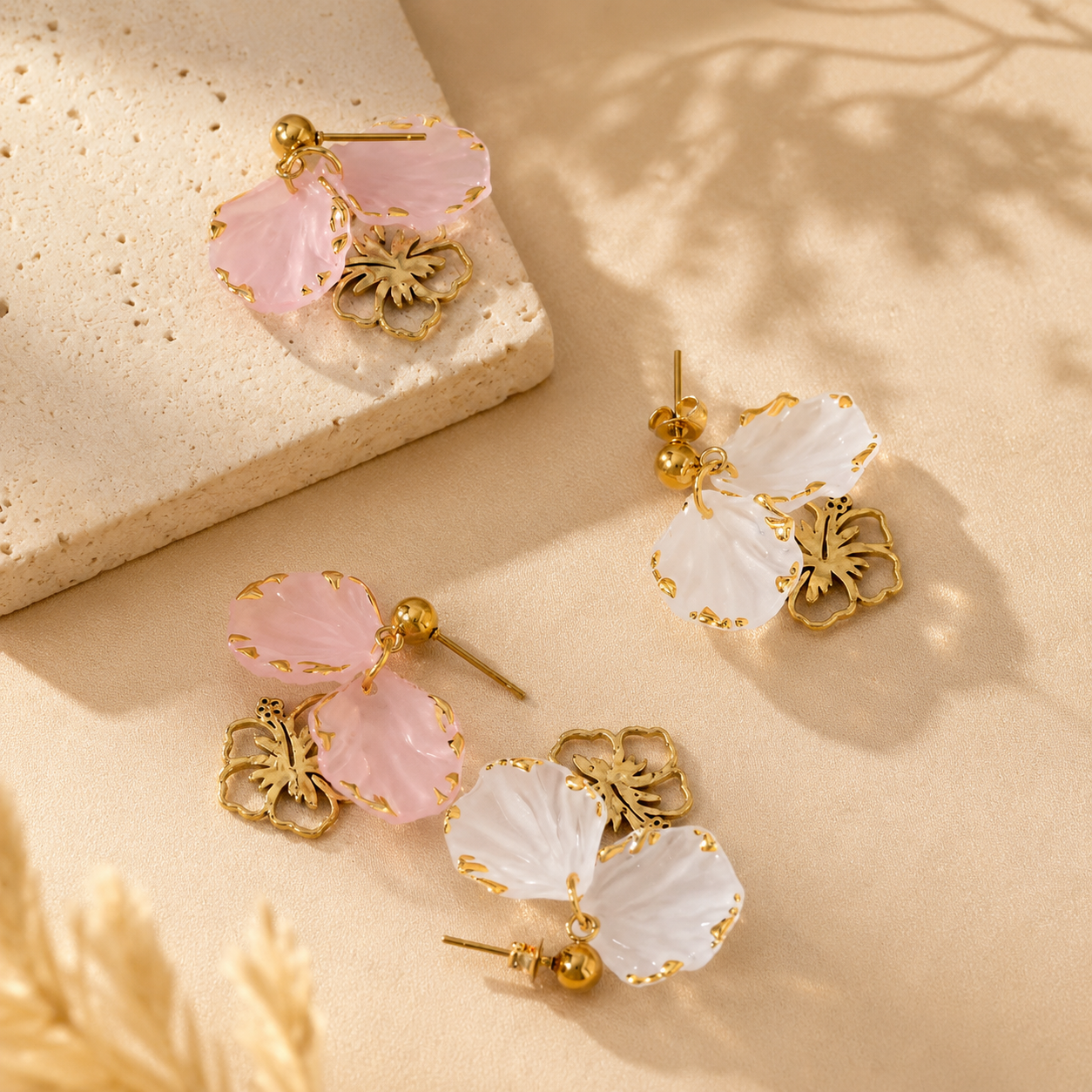 Pair of floral earrings with pink and white stones on a beige surface