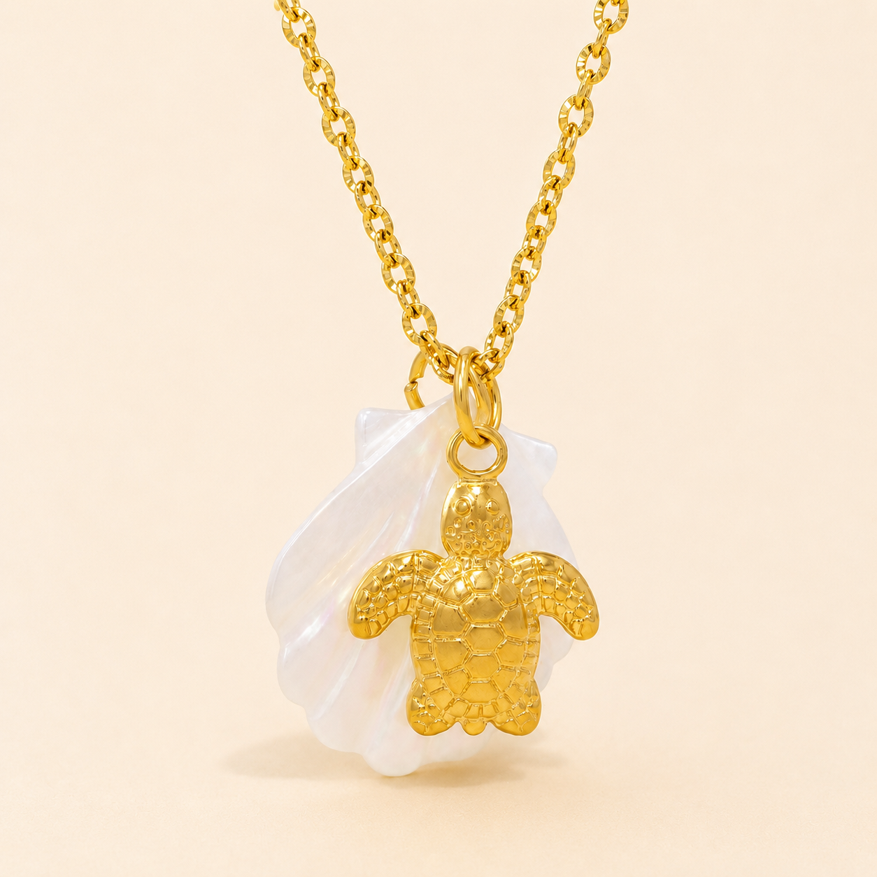 Gold turtle pendant necklace on a beige background