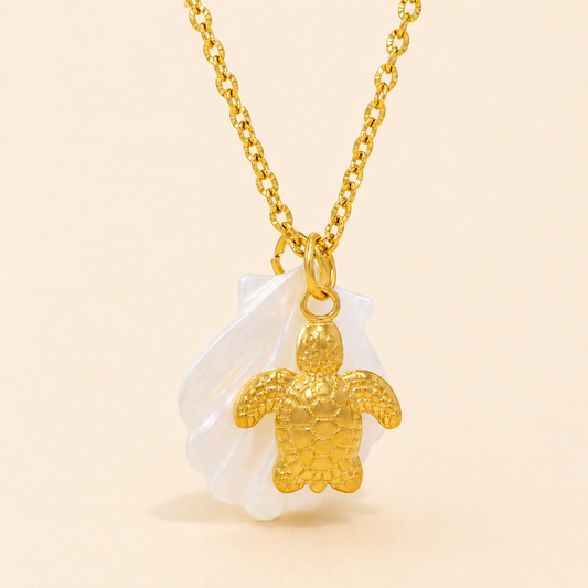 Gold turtle pendant necklace on a beige background