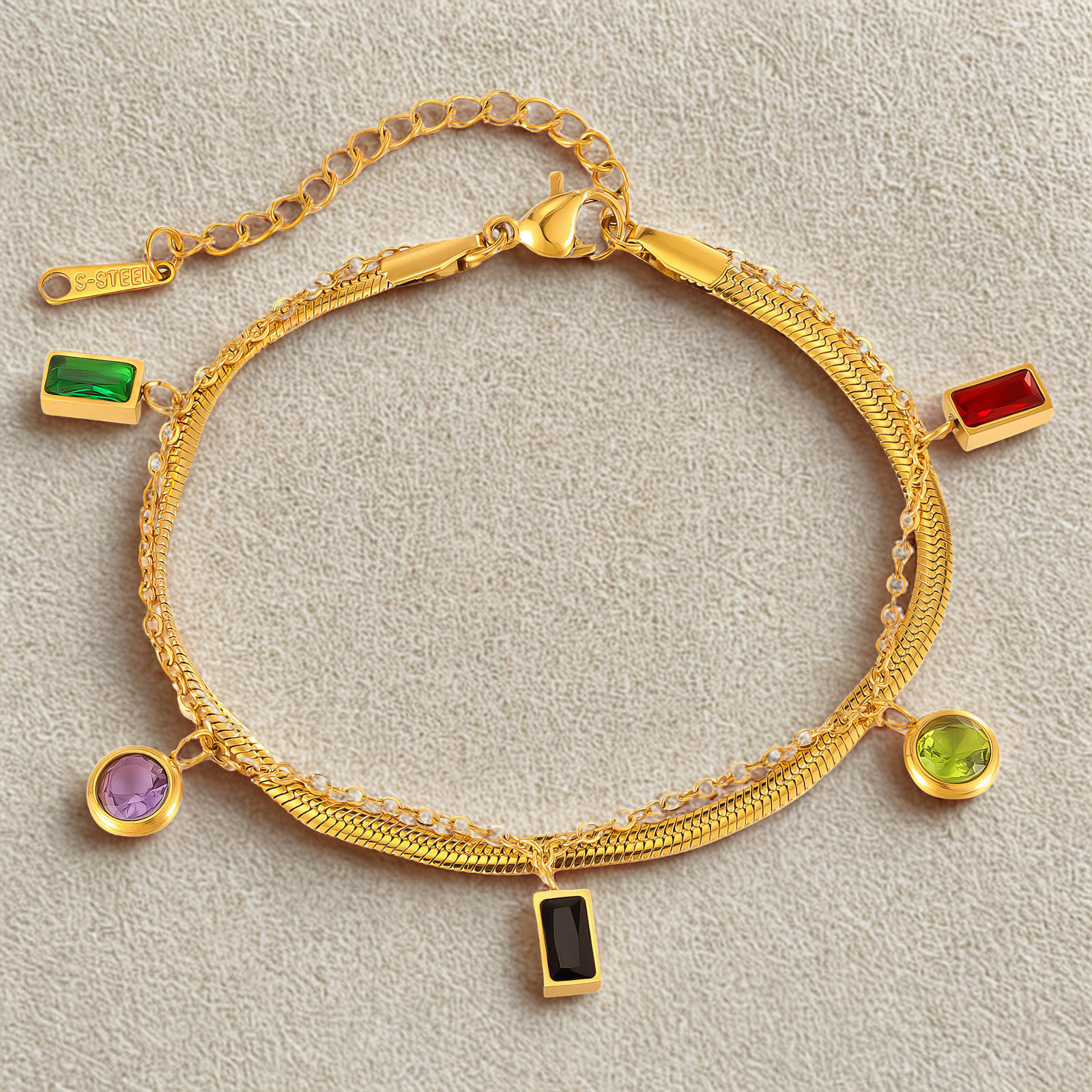 Gold bracelet with colorful gemstone charms on a light gray background