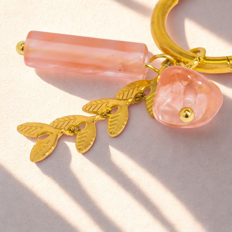 Pink keychain with gold charms on a light background