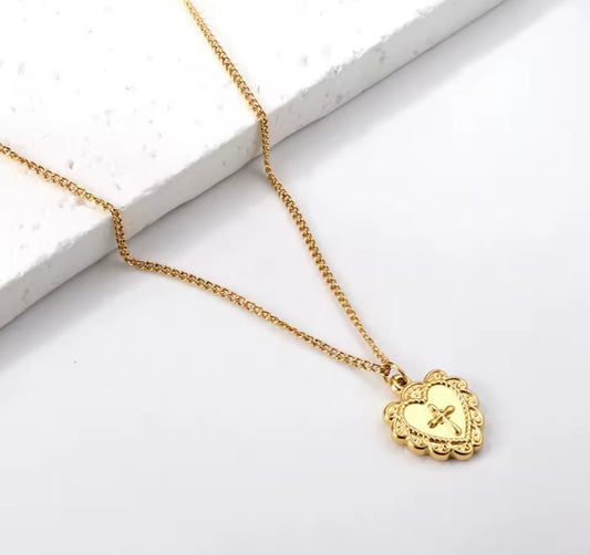 Gold necklace with a heart-shaped pendant with a cross on a white background