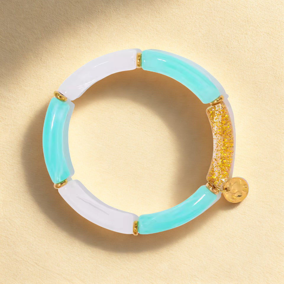 Turquoise and white bracelet with gold accents on a beige background
