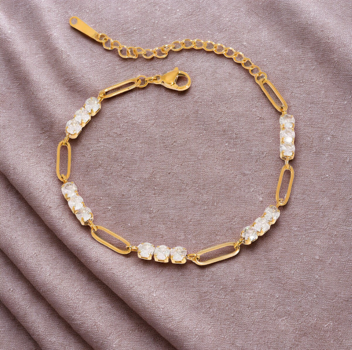 Gold bracelet with crystal stones on a soft fabric background