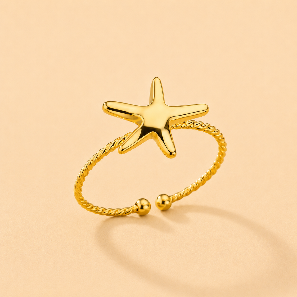 Gold starfish ring on a beige background