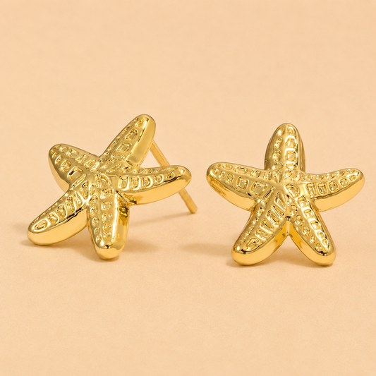 Gold starfish earrings on a beige background