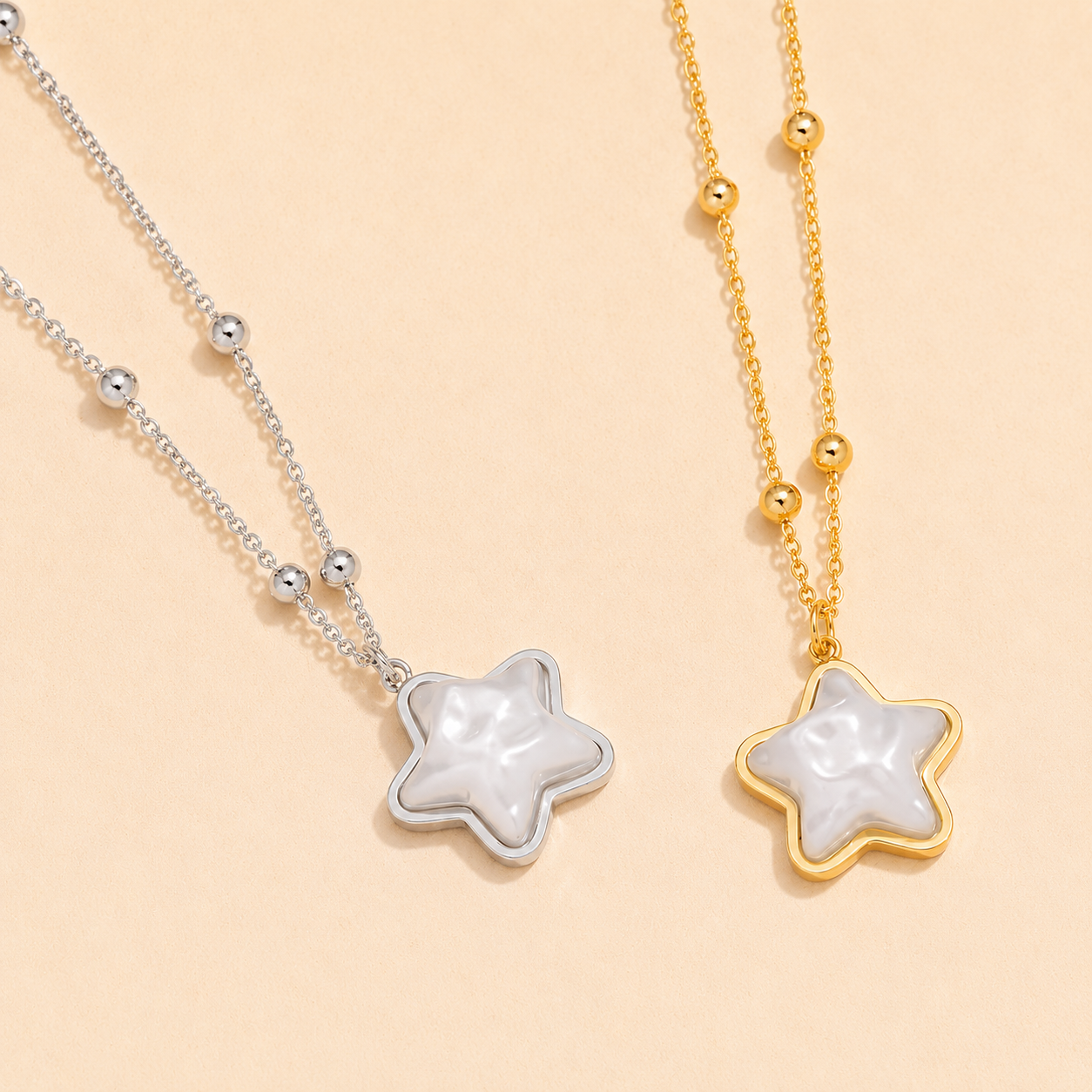 Two star-shaped pendants on gold and silver chains against a beige background