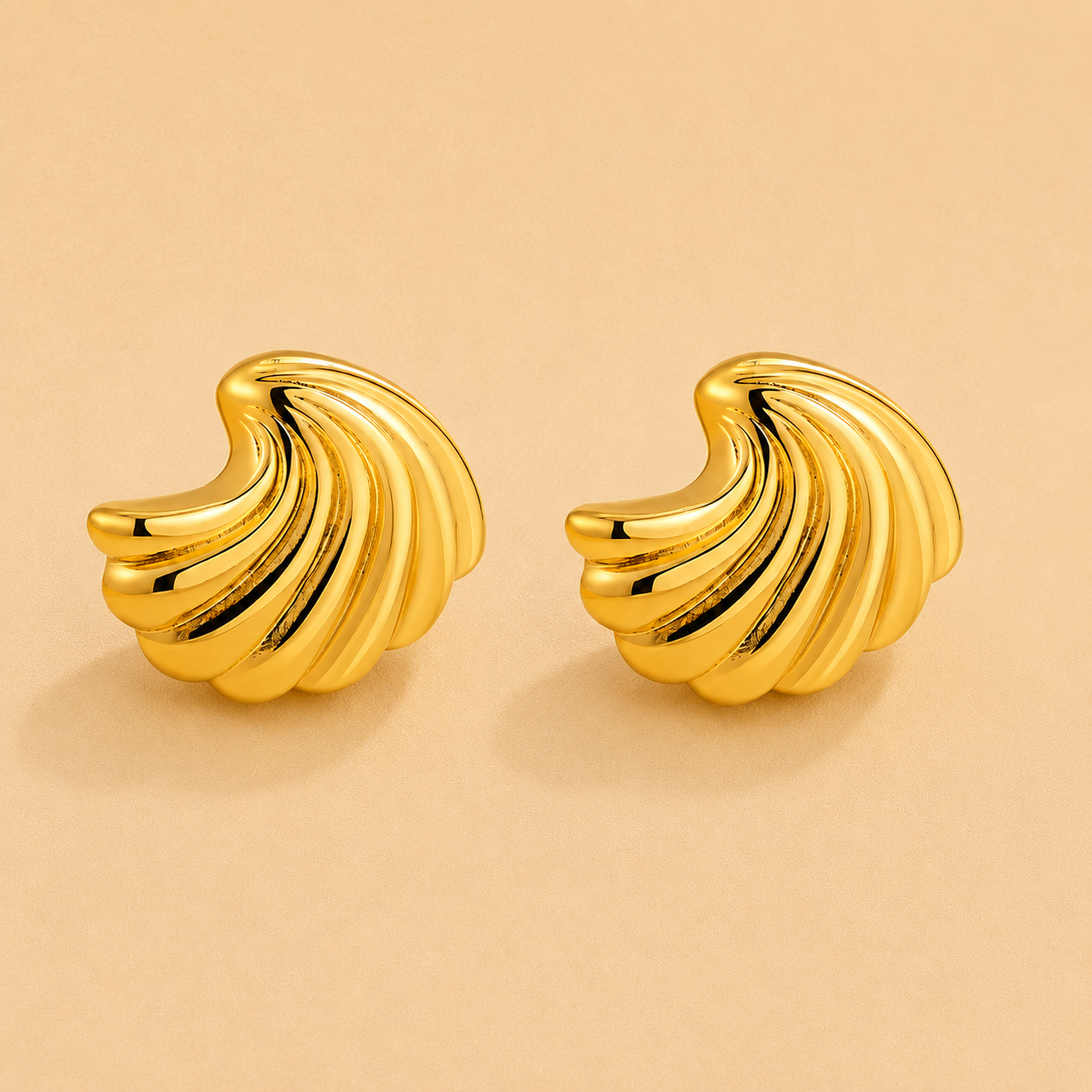 Gold shell-inspired statement earrings with a sculpted twisted design and polished finish.