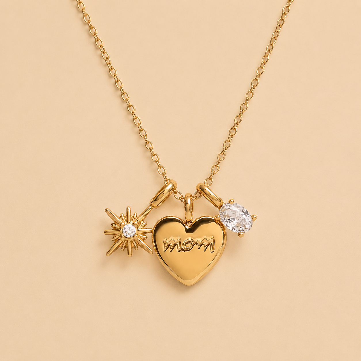 Gold necklace with heart-shaped pendant, starburst charm, and round diamond on beige background